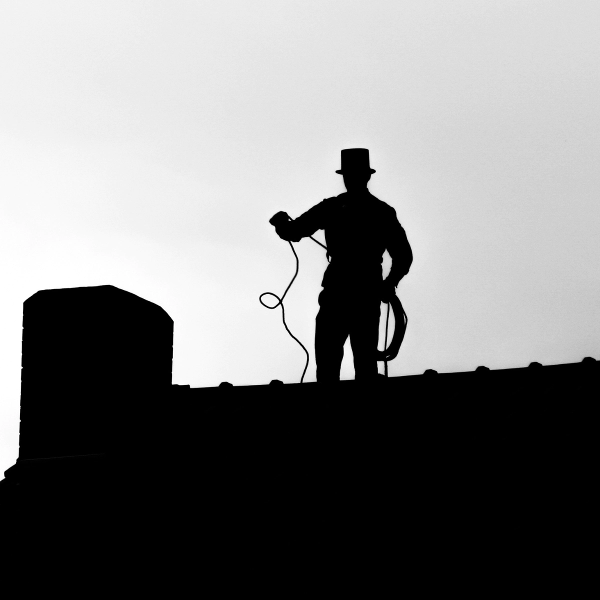 the sillhouette of a man standing on the roof of a house